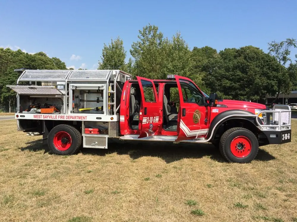 Exterior view of small fire truck showing cab, body compartments, and wheel/tire area.