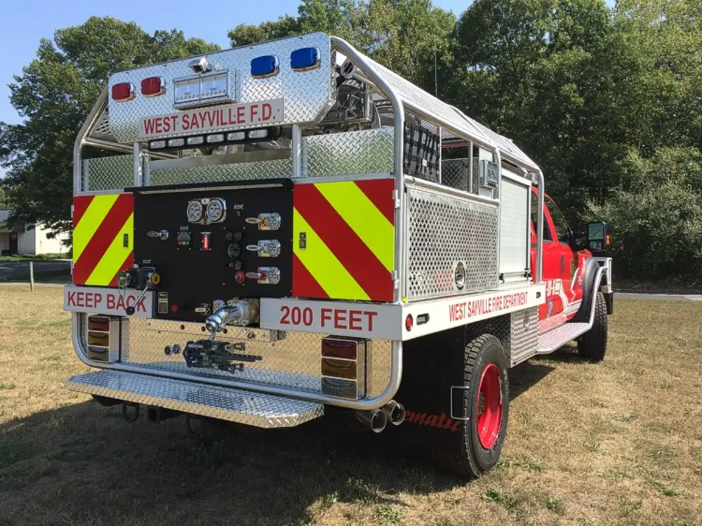 Exterior view of small fire truck showing cab, body compartments, and wheel/tire area.