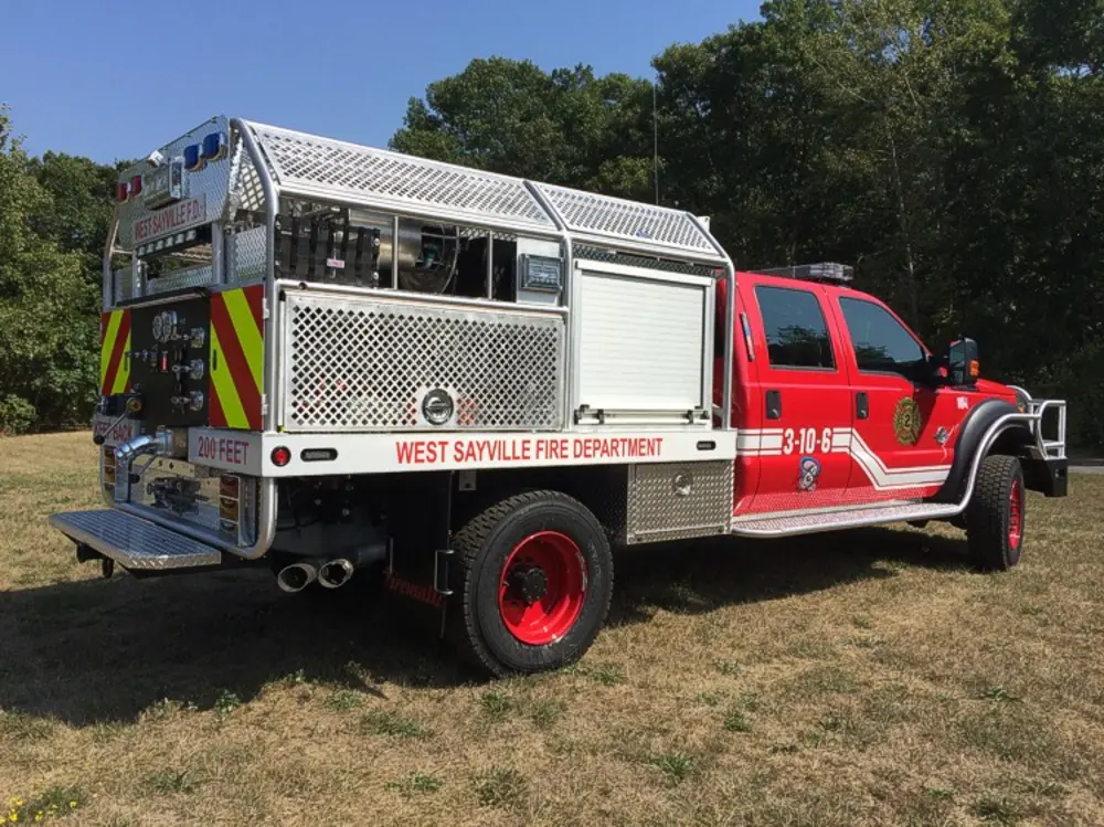 Exterior view of small fire truck showing cab, body compartments, and wheel/tire area.