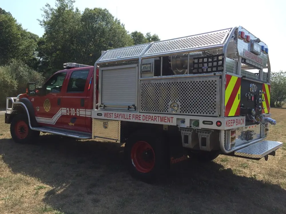 Exterior view of small fire truck showing cab, body compartments, and wheel/tire area.