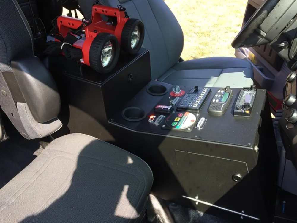Exterior view of small fire truck showing cab, body compartments, and wheel/tire area.