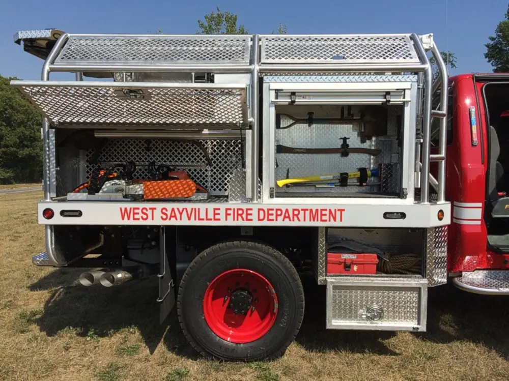 Exterior view of small fire truck showing cab, body compartments, and wheel/tire area.