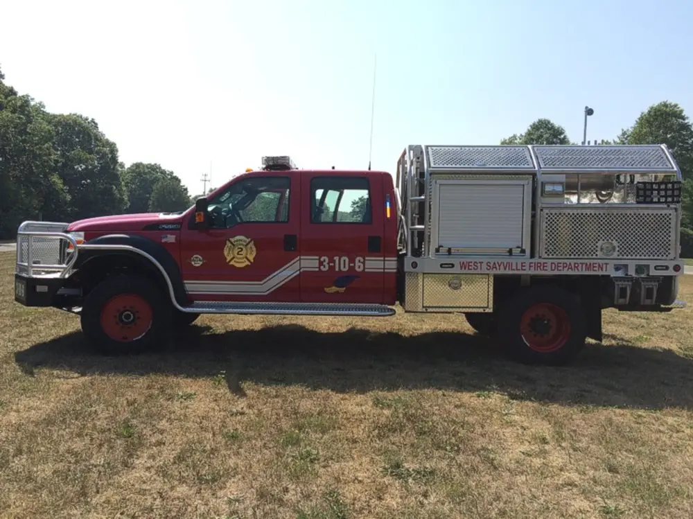Exterior view of small fire truck showing cab, body compartments, and wheel/tire area.
