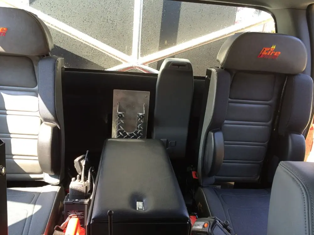 Exterior view of small fire truck showing cab, body compartments, and wheel/tire area.