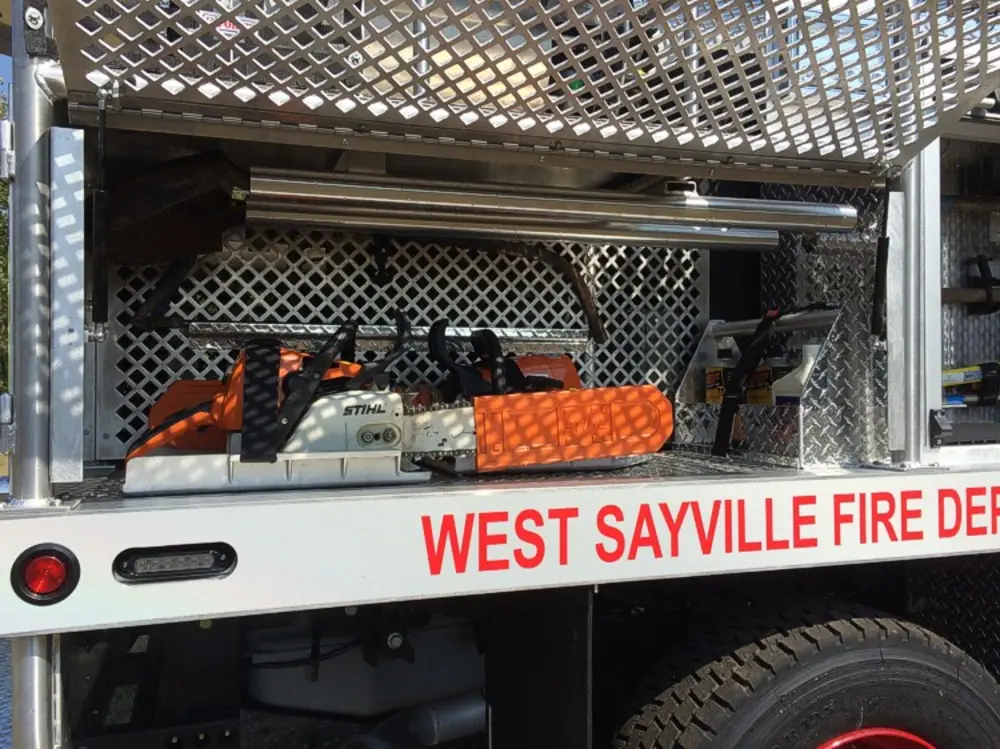 Exterior view of small fire truck showing cab, body compartments, and wheel/tire area.