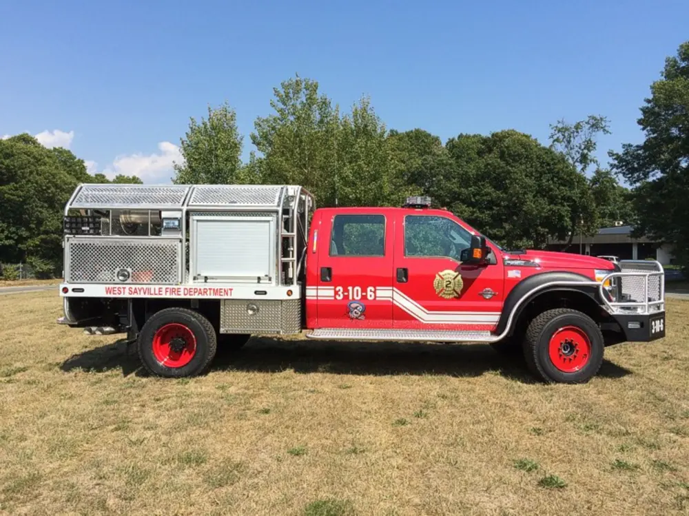 Exterior view of small fire truck showing cab, body compartments, and wheel/tire area.