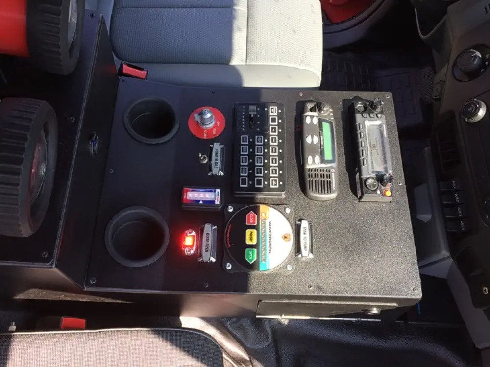 Exterior view of small fire truck showing cab, body compartments, and wheel/tire area.