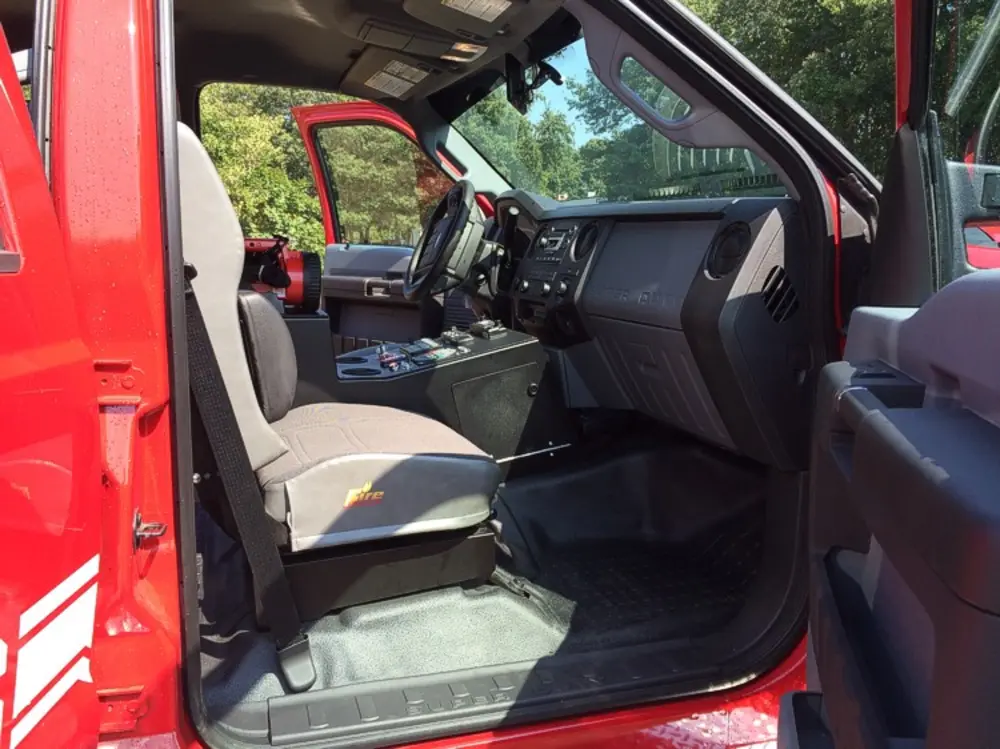 Exterior view of small fire truck showing cab, body compartments, and wheel/tire area.