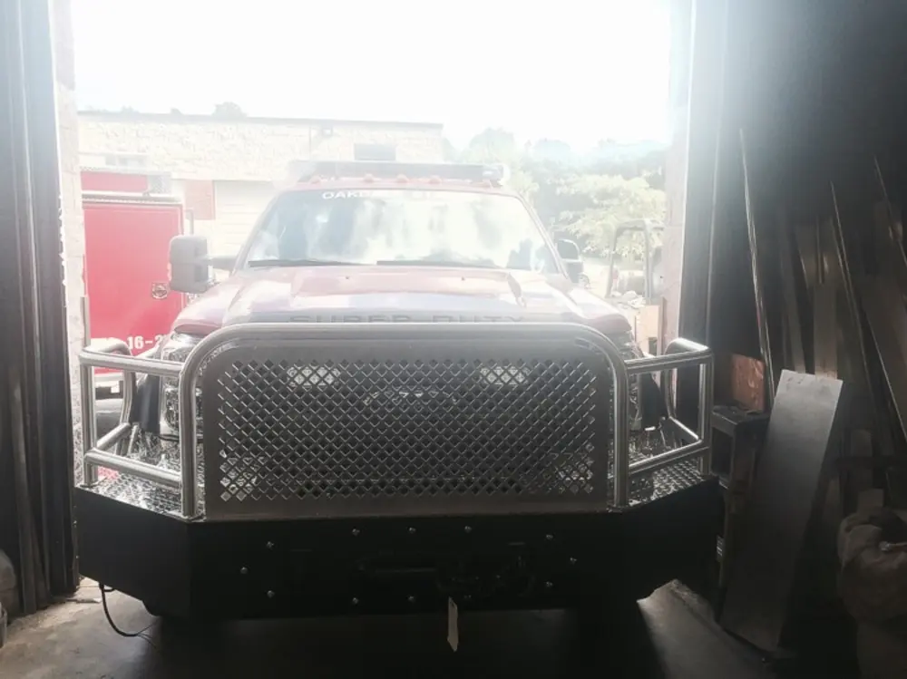 Exterior view of small fire truck showing cab, body compartments, and wheel/tire area.