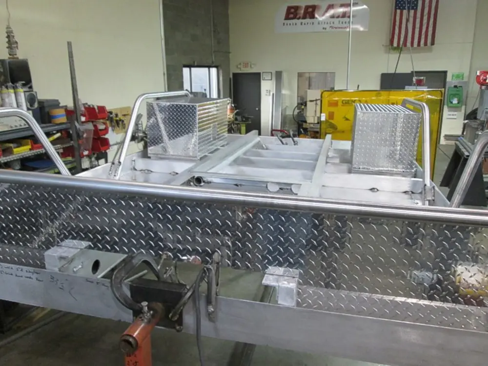 Exterior view of small fire truck showing cab, body compartments, and wheel/tire area.