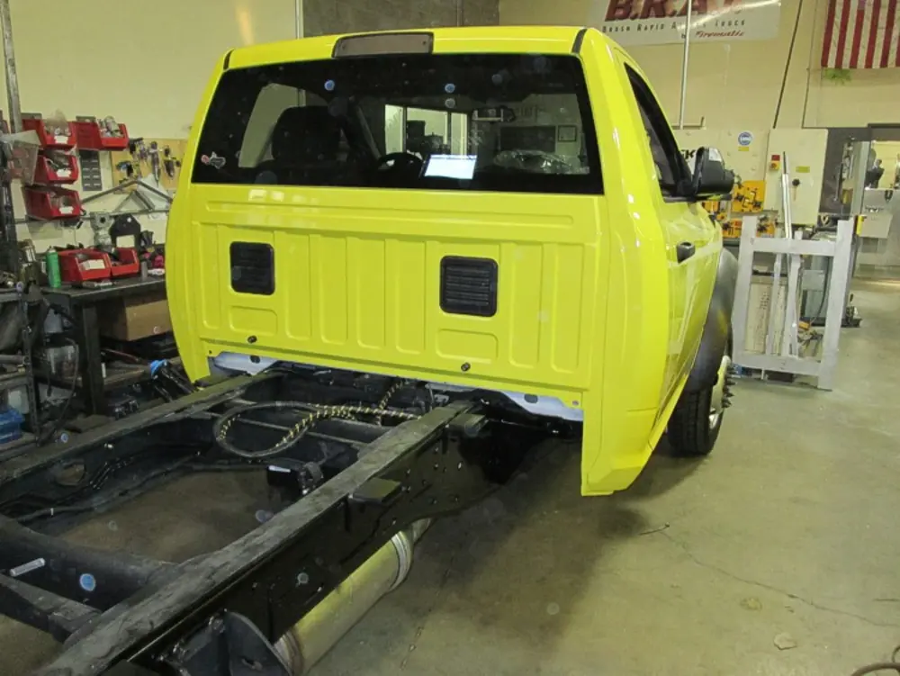 Exterior view of small fire truck showing cab, body compartments, and wheel/tire area.
