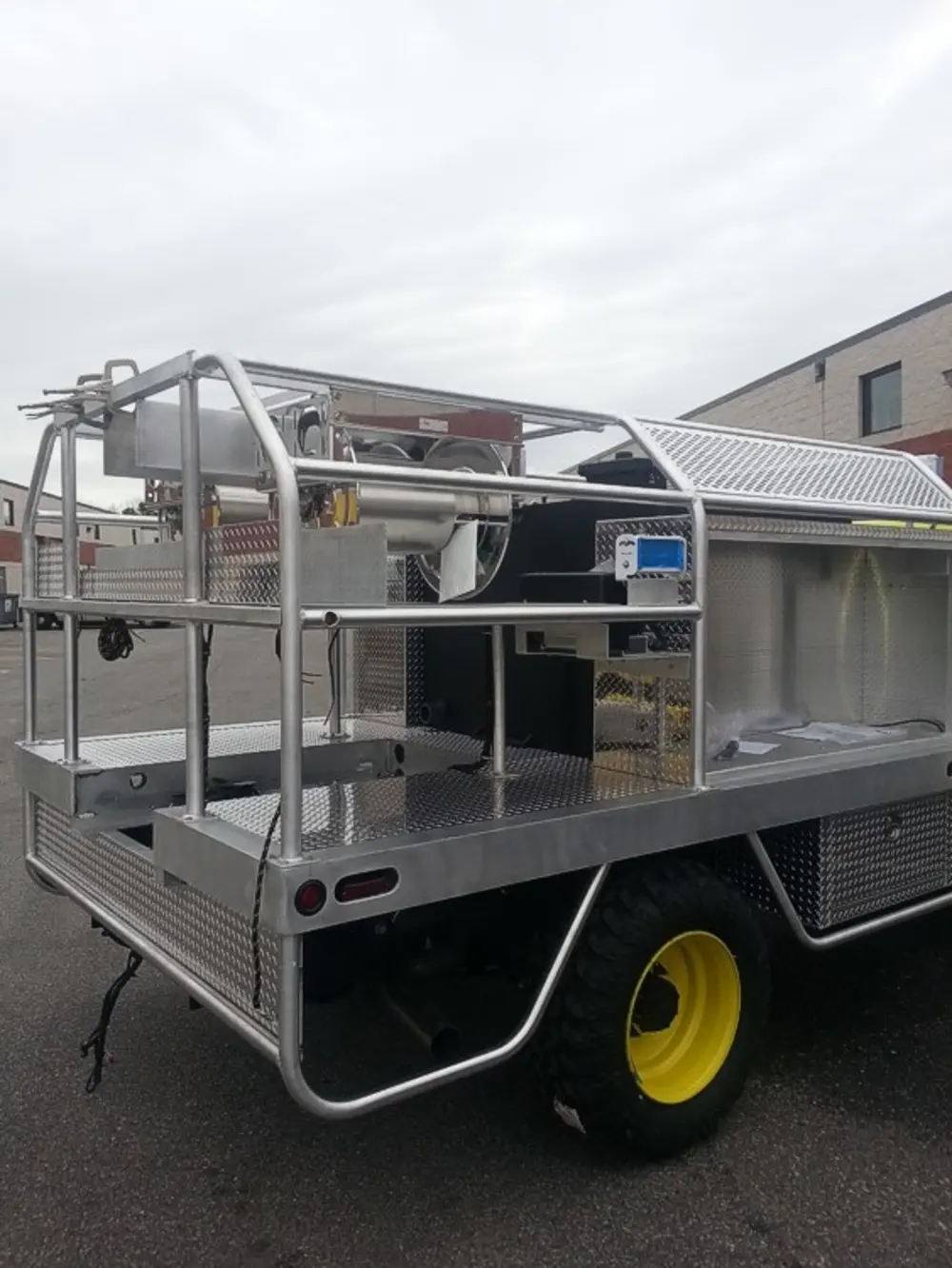 Exterior view of small fire truck showing cab, body compartments, and wheel/tire area.