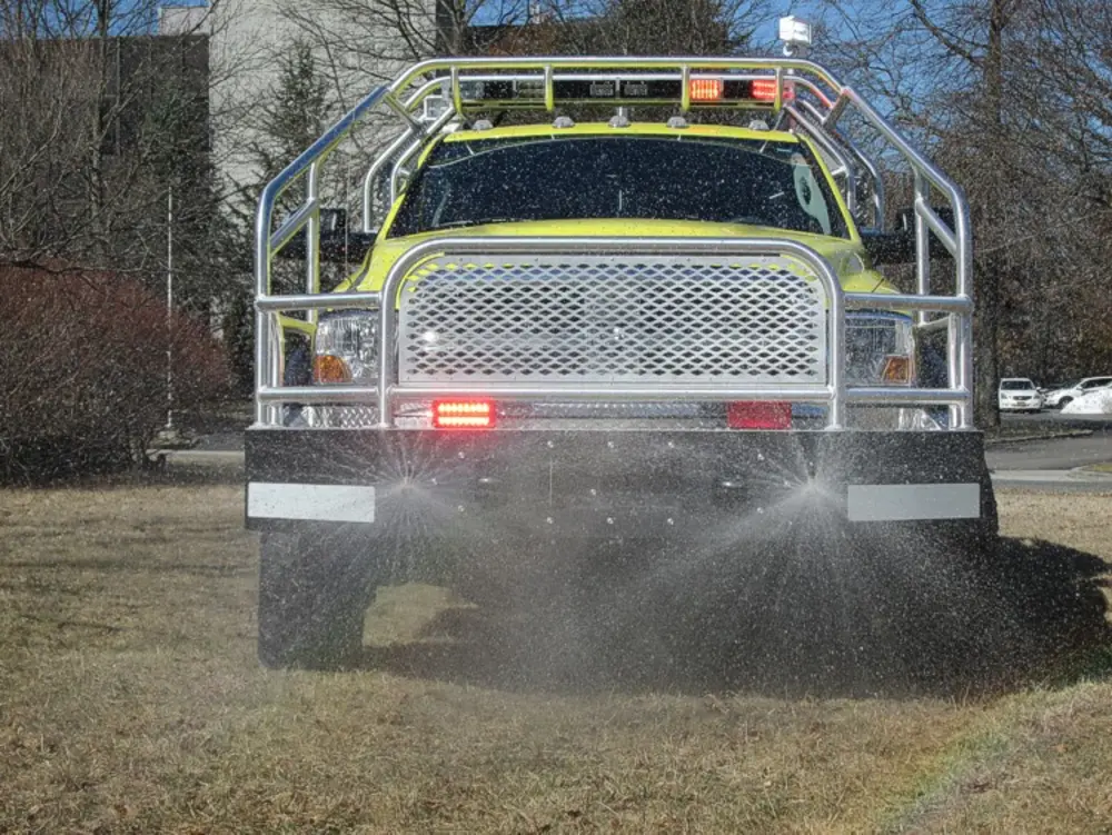 Exterior view of small fire truck showing cab, body compartments, and wheel/tire area.