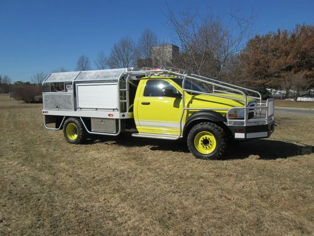 Exterior view of small fire truck showing cab, body compartments, and wheel/tire area.