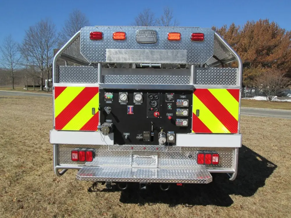Exterior view of small fire truck showing cab, body compartments, and wheel/tire area.