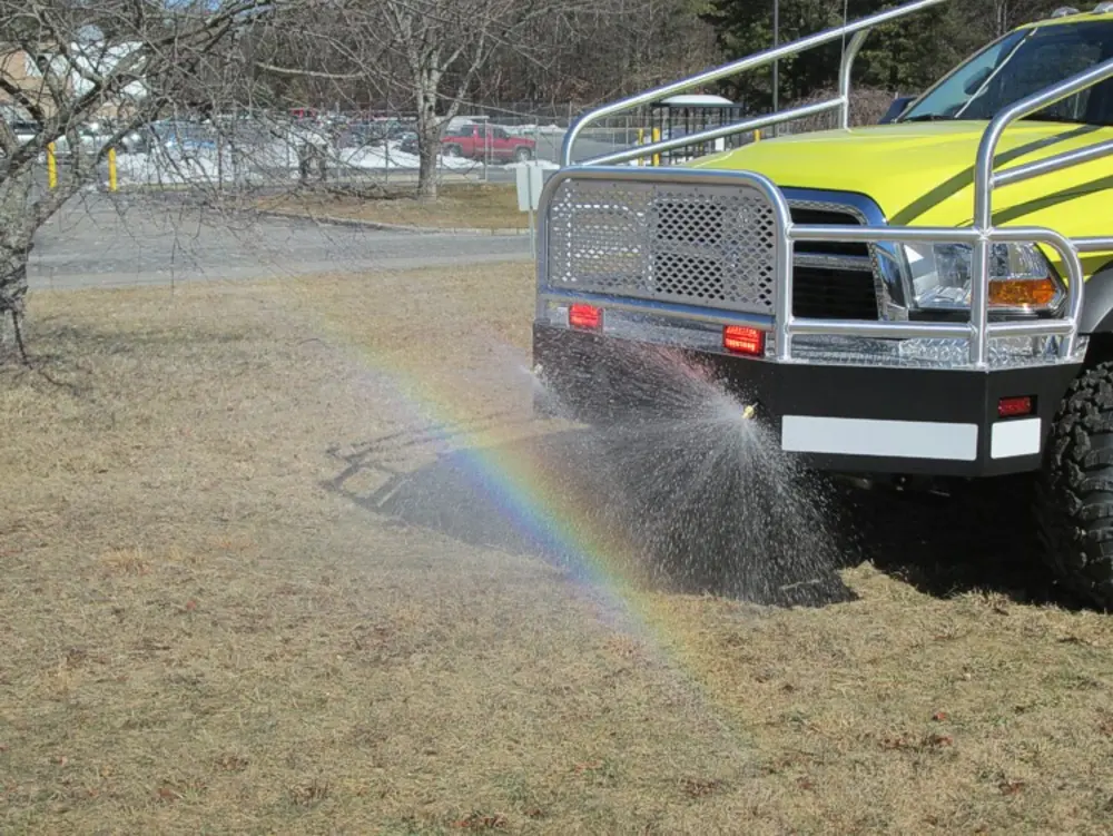 Exterior view of small fire truck showing cab, body compartments, and wheel/tire area.