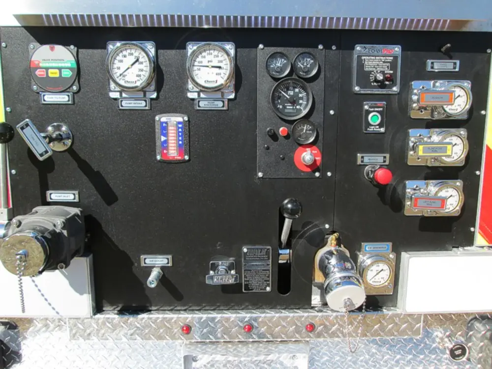 Exterior view of small fire truck showing cab, body compartments, and wheel/tire area.