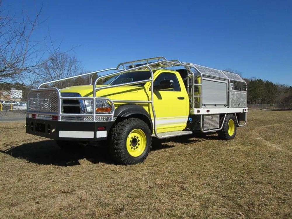 Exterior view of small fire truck showing cab, body compartments, and wheel/tire area.