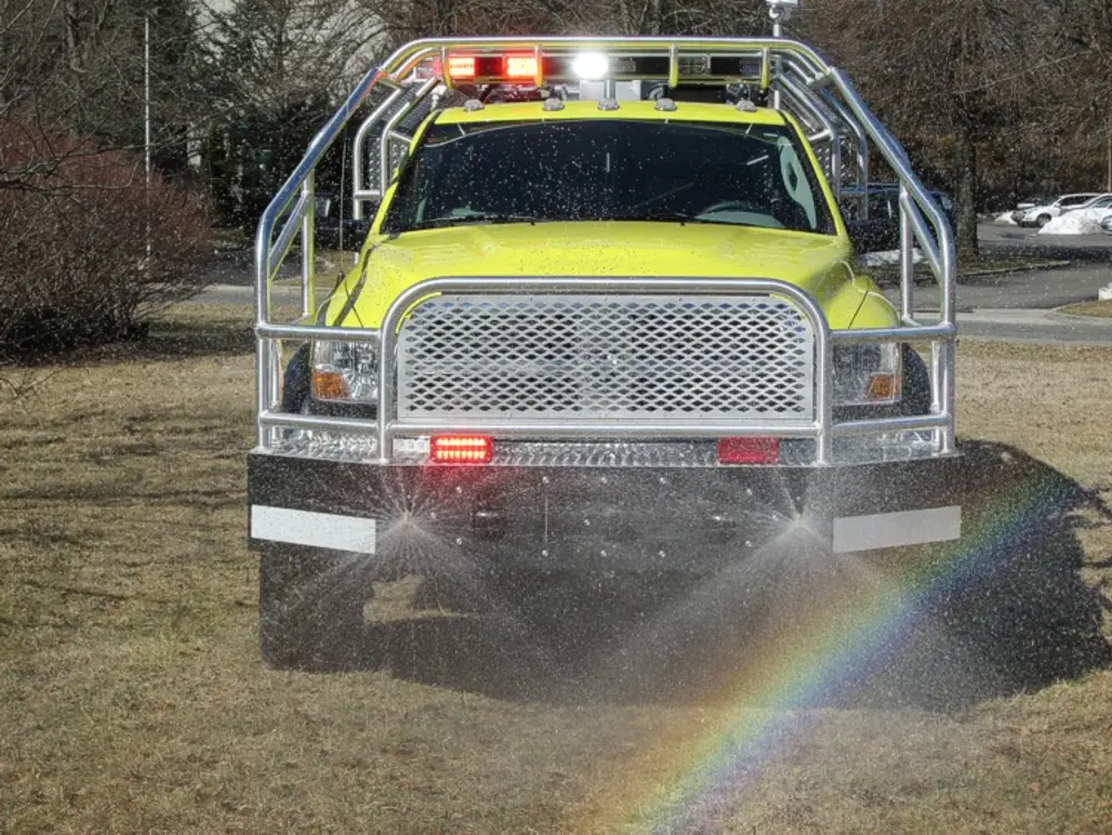 Exterior view of small fire truck showing cab, body compartments, and wheel/tire area.