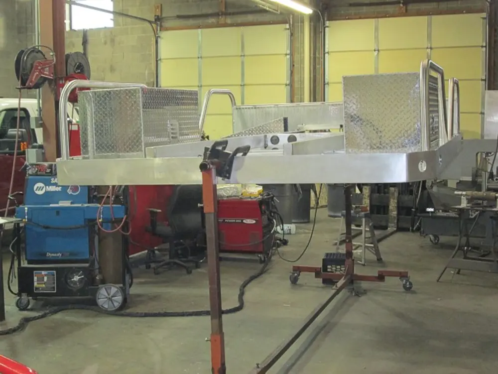 Exterior view of small fire truck showing cab, body compartments, and wheel/tire area.