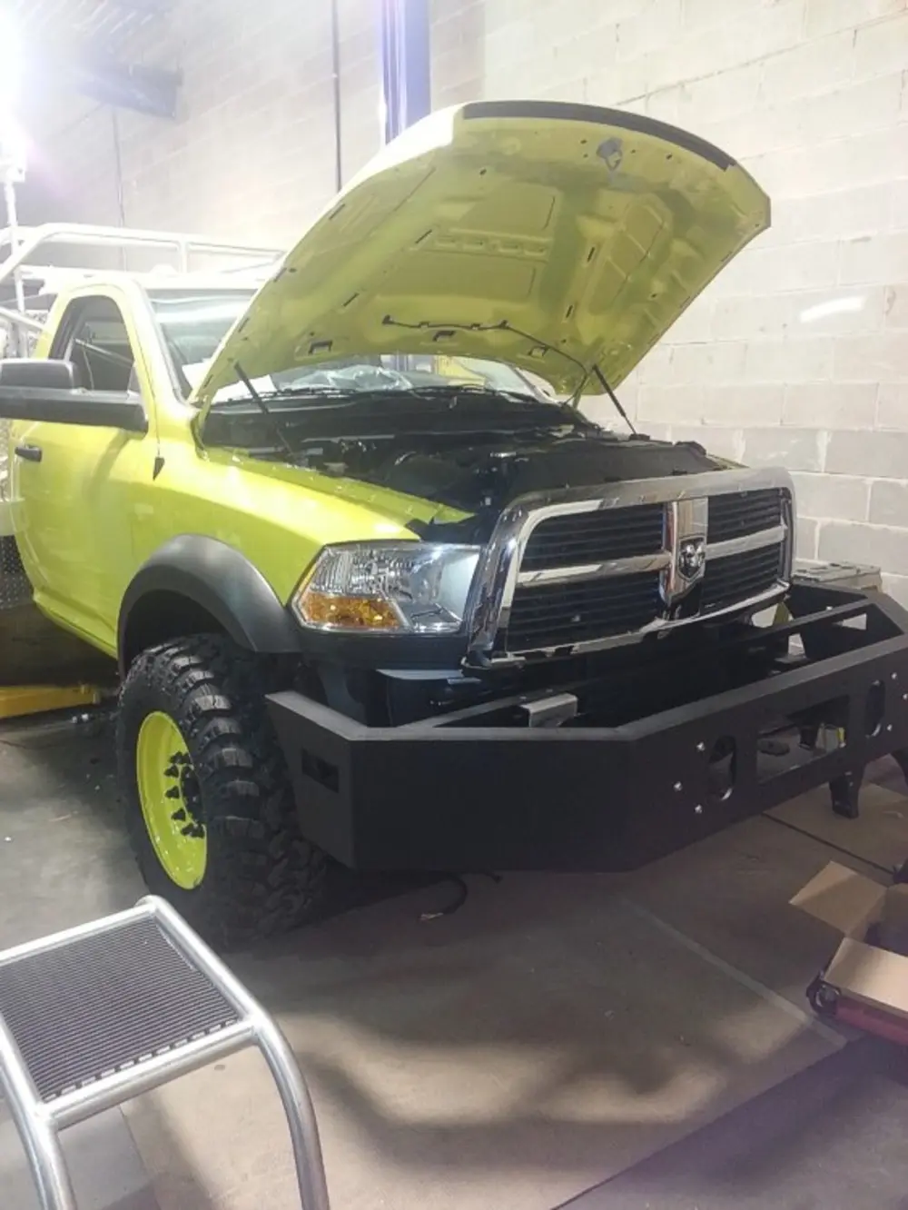 Exterior view of small fire truck showing cab, body compartments, and wheel/tire area.