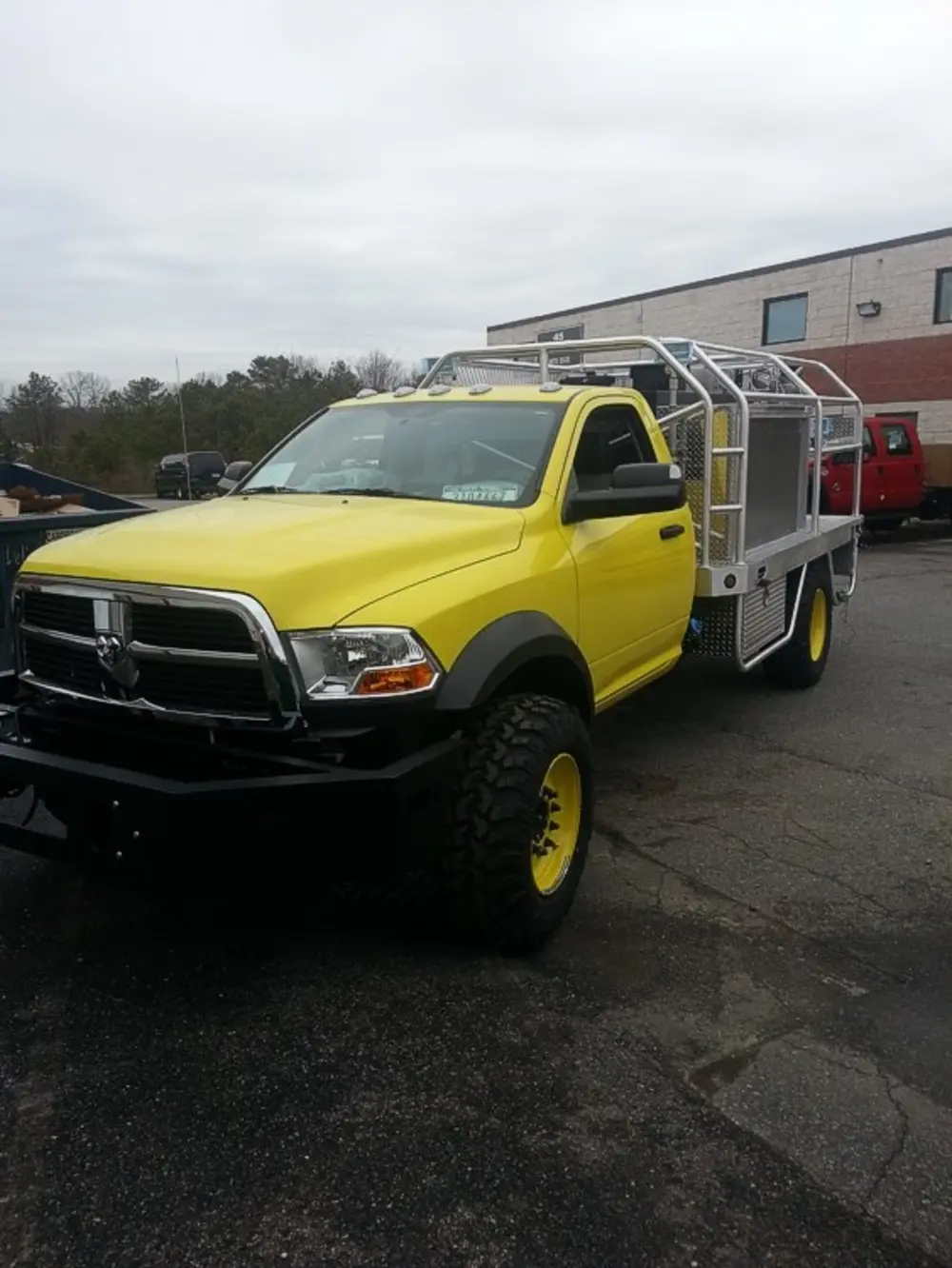 Exterior view of small fire truck showing cab, body compartments, and wheel/tire area.