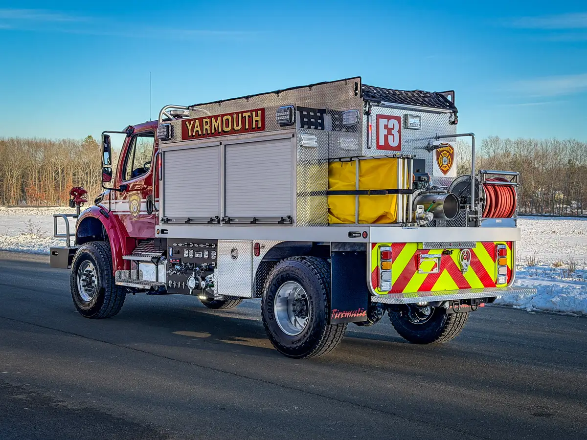 Rear-left three-quarter exterior view with chevron rear panel, hose reel, and rear platform.
