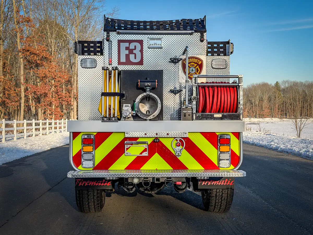 Straight rear exterior view showing chevron striping, dump outlet, and rear hose reel.
