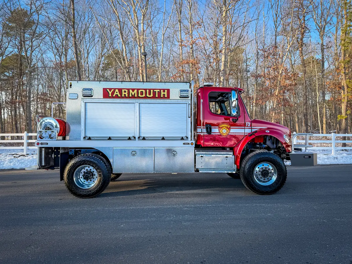 Right side profile with side compartments closed, rear hose reel, and wheel/tire area visible.