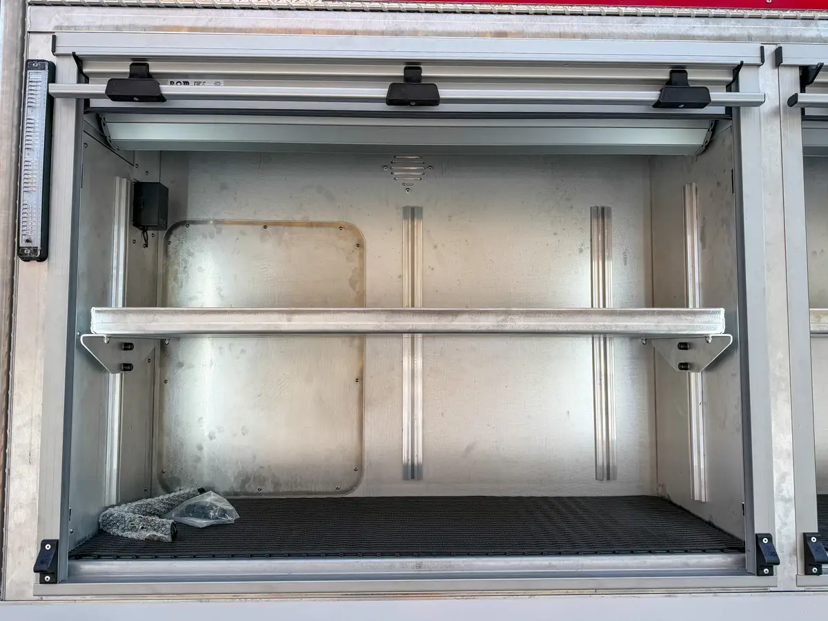 Close-up of an open upper side compartment with adjustable shelf and interior light.