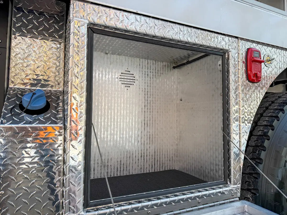 Close-up inside the open lower side compartment near the rear wheel arch.