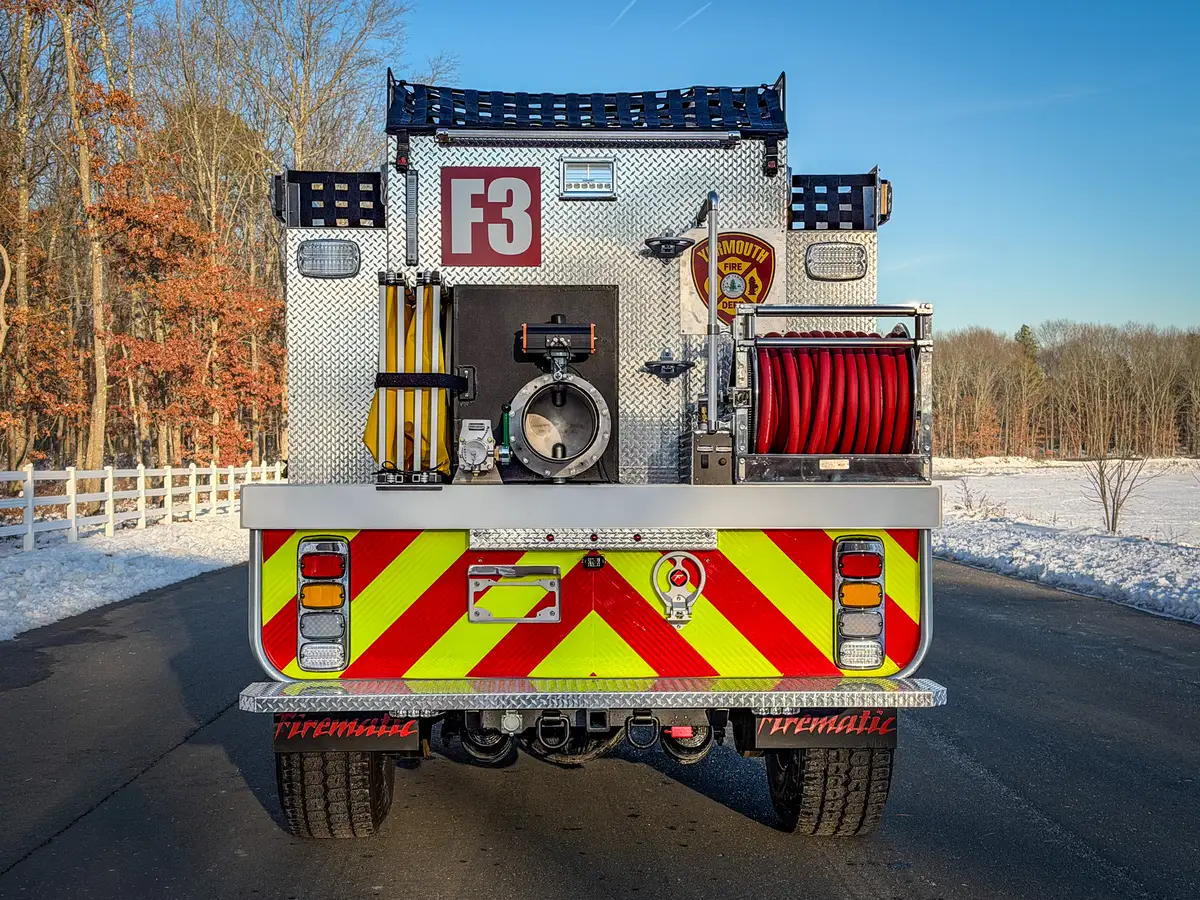 Rear view close-up of dump outlet assembly, folded dump tank, and hose reel.