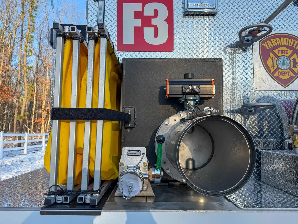 Close-up of rear dump chute intake next to the folded portable tank.