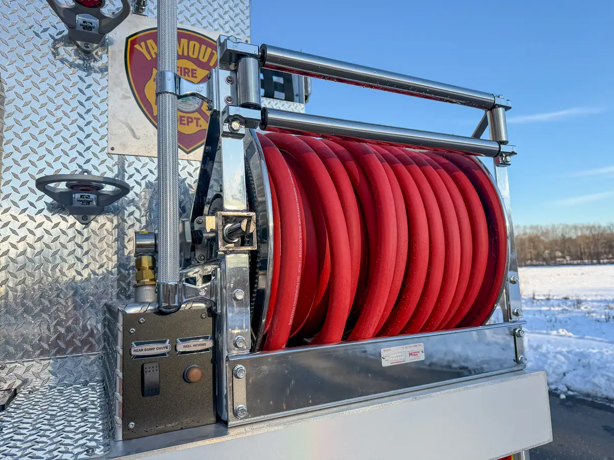 Close-up of rear hose reel loaded with red hose and reel controls.