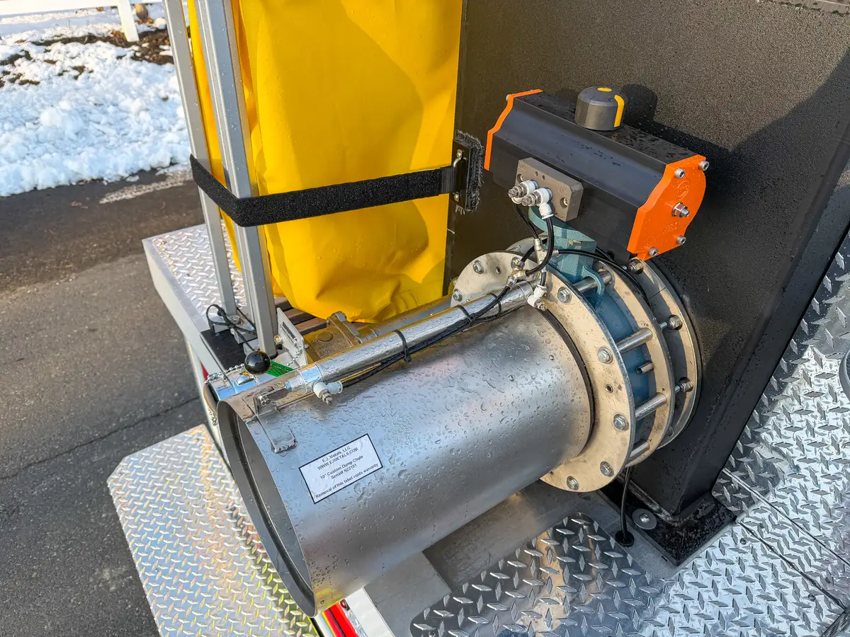 Close-up of rear dump chute body and actuator mounted beside folded tank.