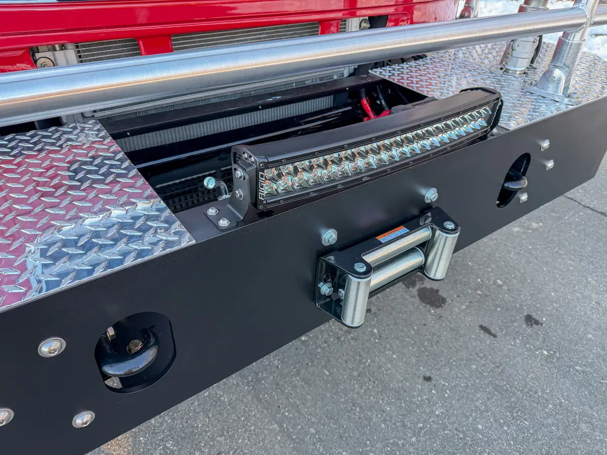 Close-up of front bumper winch roller fairlead and LED light bar.