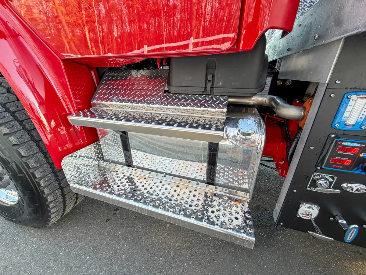 Right-side cab view showing steps, front wheel area, and pump controls.