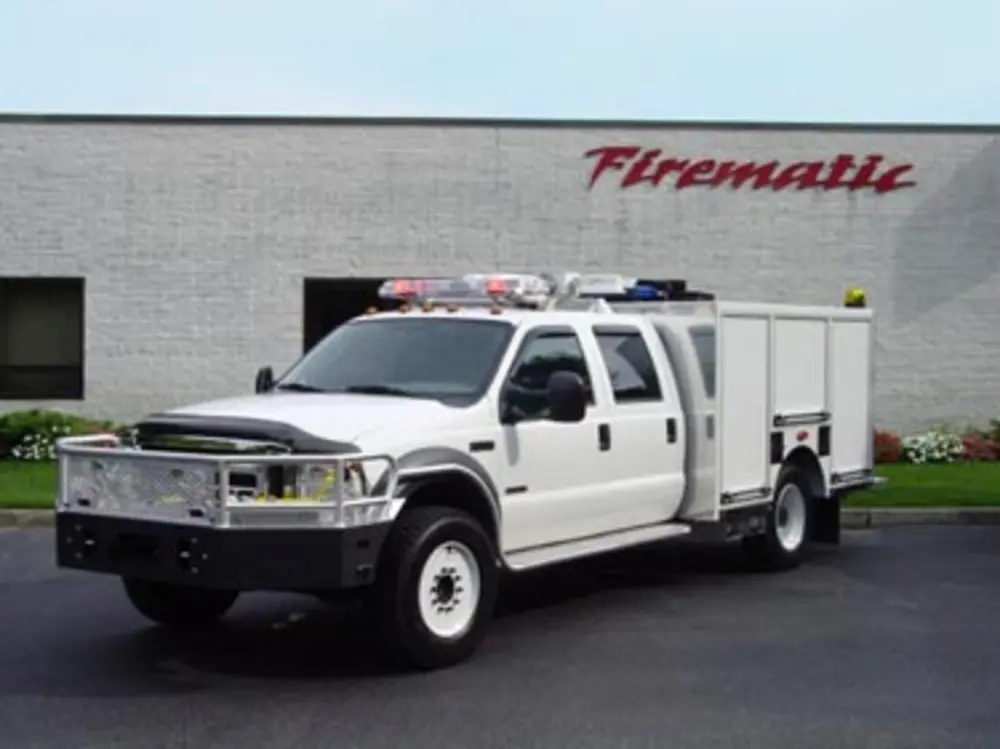 Exterior view of small fire truck showing cab, body compartments, and wheel/tire area.