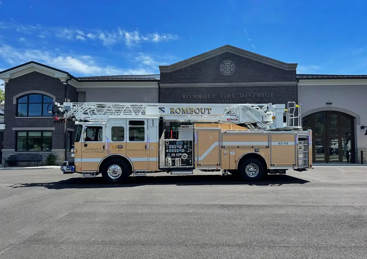 Aerial ladder truck full side profile parked in front of a fire station