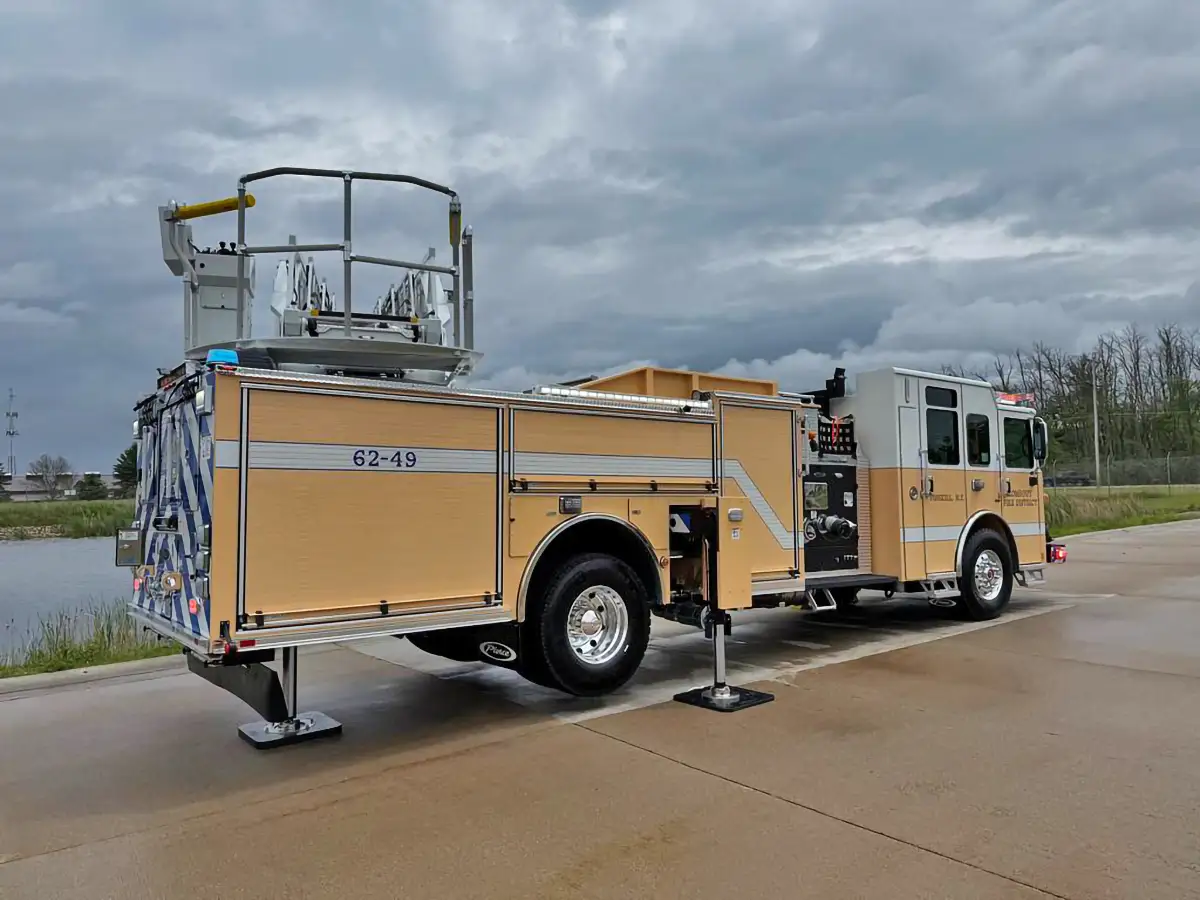 Rear-right exterior view with stabilizer outriggers deployed and bucket raised