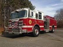 Wide front-right view of the pumper parked roadside with full side body visible.