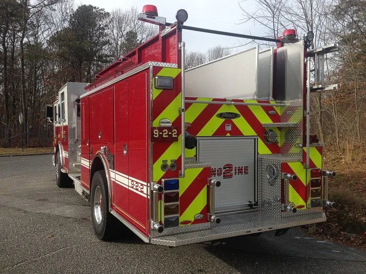 Rear-right exterior view with red-yellow chevrons, rear body panel, and side compartments.