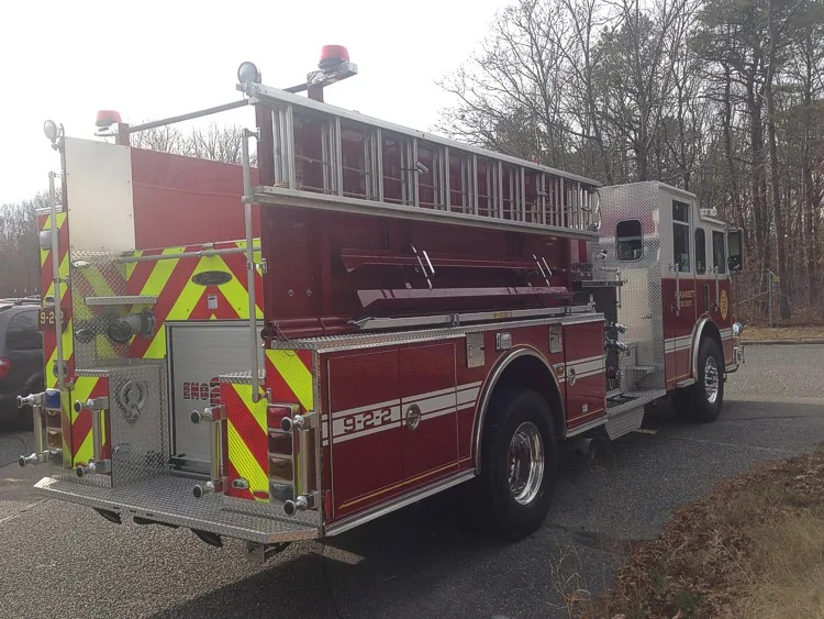 Rear-left exterior view showing side ladder rack, rear chevron panel, and hosebed area.