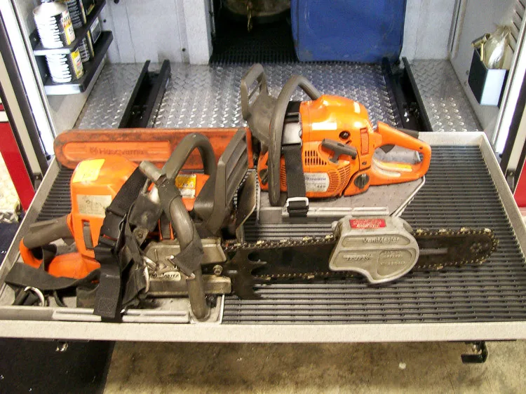 Open side compartment showing mounted rescue saw and power tools