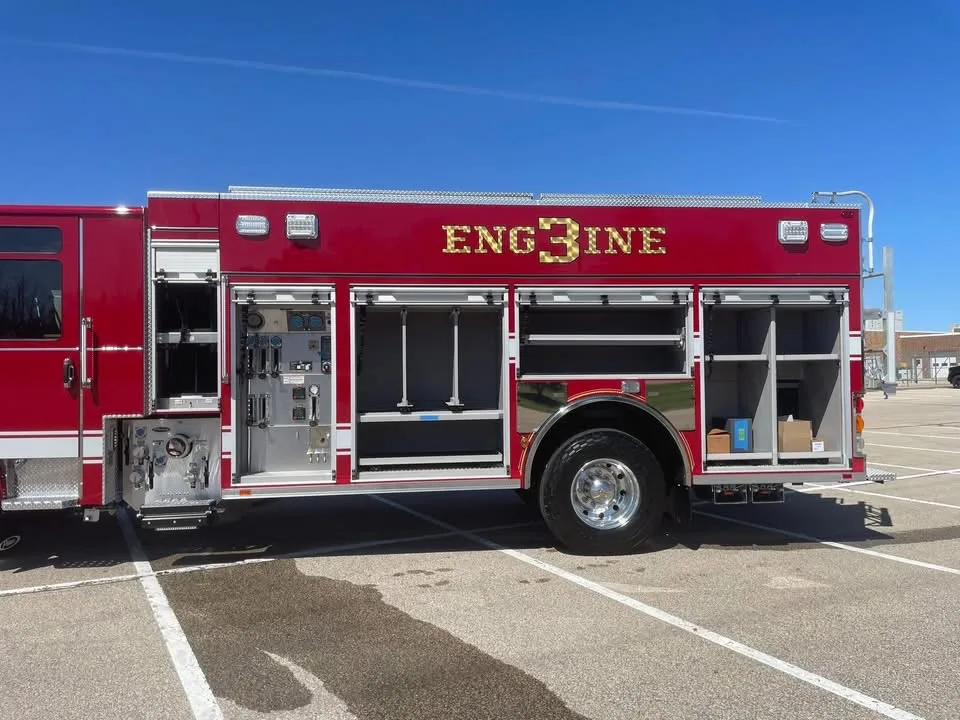 Driver-side mid-body view with compartments open showing pump controls and equipment shelves