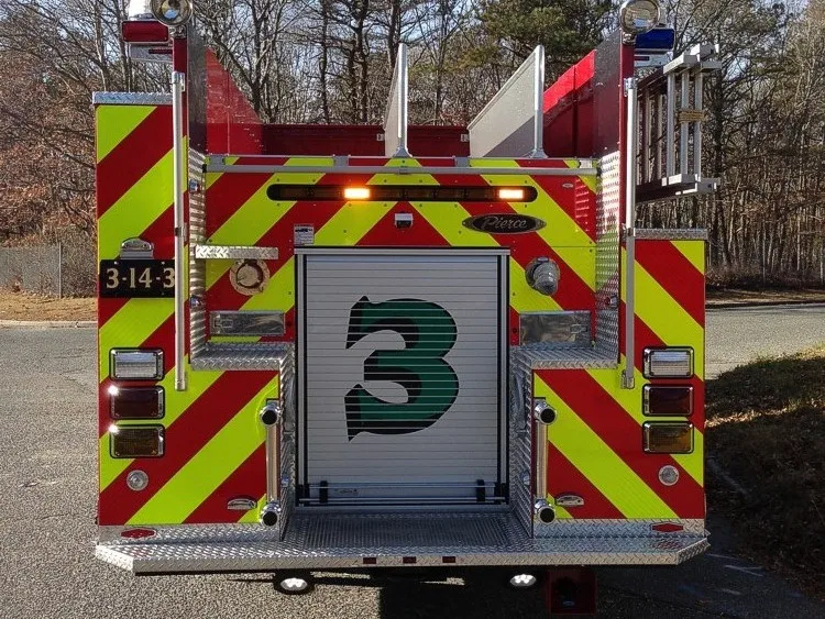 Straight rear view with red-yellow chevrons, rear fittings, and center rear roll-up door.