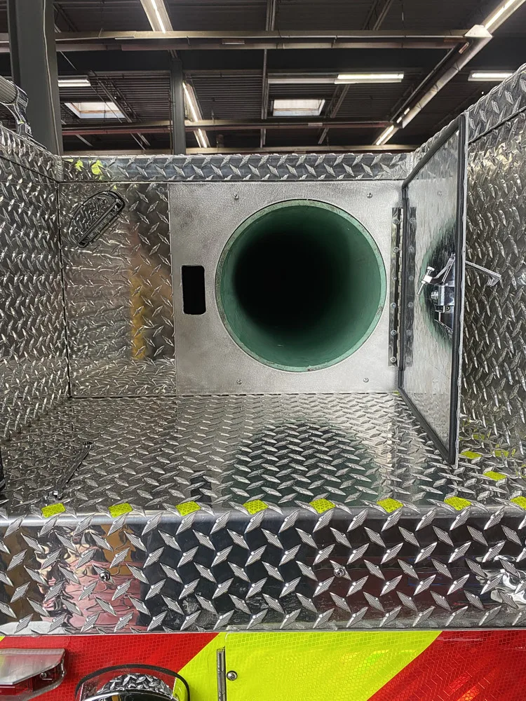 Top-down compartment view showing circular tube opening in diamond-plate well