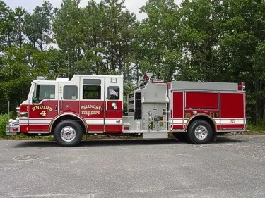 Driver-side full profile showing pump panel section, side compartments, and wheel/tire area.