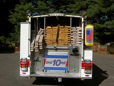 Rear view showing open hosebed with stacked hose and rear warning lights