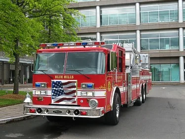 Head-on front view showing chrome bumper, flag-style grille, warning lights, and windshield.